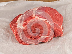Raw beef clod on white wrapping paper closeup photo