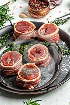 Raw beef filet Mignon steak on metel tray with pepper and salt, filet mignon. beef tenderloin steaks wrapped in bacon and thyme on