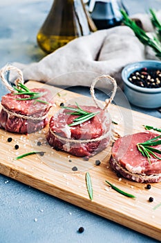 Raw beef filet mignon steak on a wooden board with rosemary and spices
