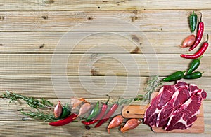 Raw beef with fresh vegetables on wooden background
