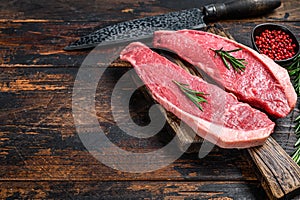 Raw beef meat cap sirloin steak on a cutting board. Dark wooden background. Top view. Copy space