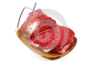 Raw beef meat chunk and slices on cutting plate