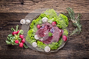 Raw beef meat with fresh vegetable. Sliced beef steak in lettuce salads radishes and mushrooms