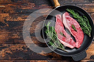 Raw beef meat rump steak in a pan. Dark wooden background. Top view. Copy space