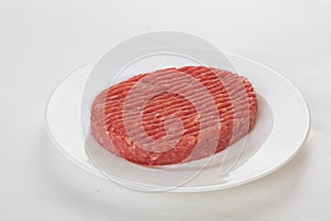 Raw beef patties on a plate isolated