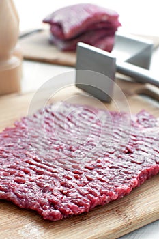 Raw beef round steak and pounder