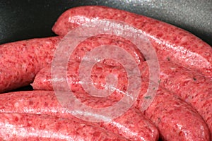 Raw beef sausages in a pan