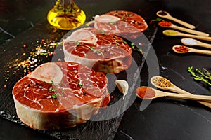 Raw beef shank and spices for preparing ossobuco dish on black background