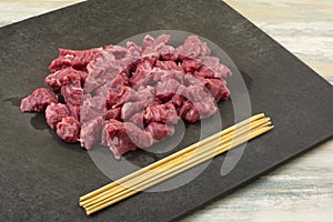 Raw beef sirloin cubes and wooden skewers