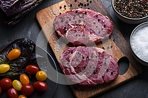 Raw beef sirloin steak with peppercorn and salt on cutting board