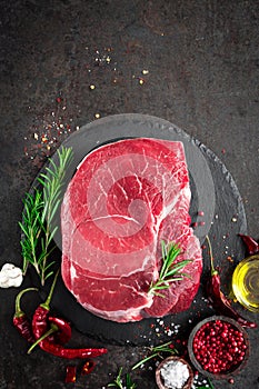 Raw beef steak on black background with cooking ingredients. Fresh beef meat