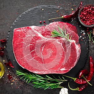 Raw beef steak on black background with cooking ingredients. Fresh beef meat