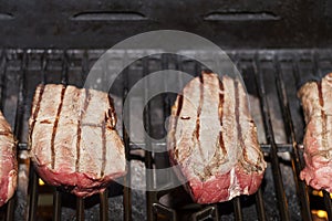 Raw beef steak cooking over flaming grill