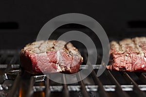 Raw beef steak cooking over flaming grill