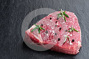 Raw beef steak with herbs on a dark stone slate