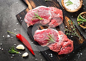 Raw beef steak with herbs top view.