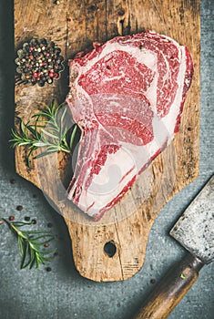 Raw beef steak rib-eye on board with seasoning, top view