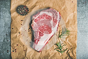 Raw beef steak rib-eye with seasoning on craft paper