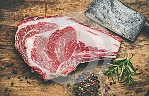 Raw beef steak rib-eye with seasoning and knife, rustic background