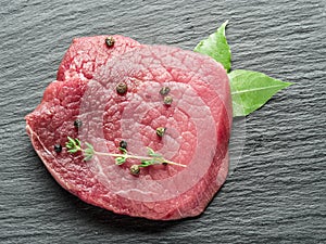 Raw beef steaks with spices on the cutting board.