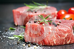 Raw Beef Steaks with spices and Rosemary over Slate