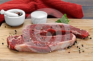 Raw beef strip steaks on a cutting board.