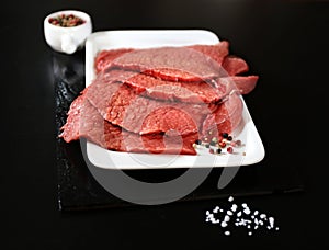 Raw beef tenderloin, salt, pepper and a knife