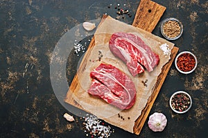 Raw beef tenderloin. Steaks on a cutting board with spices on a dark background. Top view, copy space.