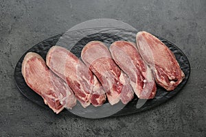 Raw beef tongue pieces on grey table, top view