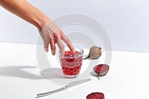 Raw beets and a glass of juice on a white table. Creative minimalistic concept