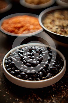 Raw black beans in ceramic bowl. Selective focus