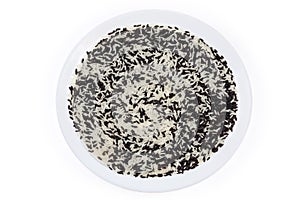 Raw black and white rice mixture on dish, top view
