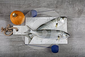 Raw Bluefish. Latin; Pomatomus Saltatrix. Fresh fish with the vegetables, condiment and lemon, bluefish. Food preparation photo