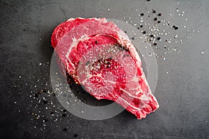 Raw Bone-In Ribeye Steak Seasoned with Kosher Salt and Black Pepper