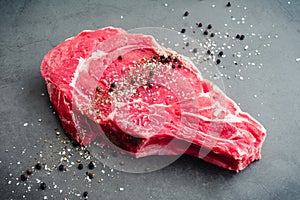 Raw Bone-In Ribeye Steak Seasoned with Kosher Salt and Black Pepper