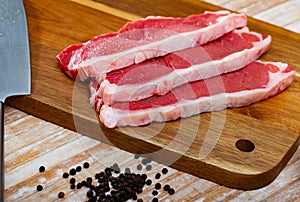 Raw boneless beef with seasonings on wooden background
