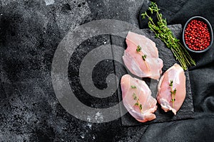 Raw boneless chicken thighs fillet. Black background. Top view. Copy space photo