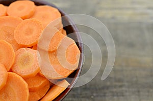 Raw bowl with sliced carrot on wooden rustic