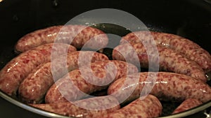 Raw brats sizzling in pan