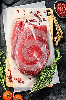 Raw brisket beef cut on a wooden cutting board. Black Angus beef. Black background. Top view