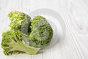 Raw broccoli on white wooden table, side view.