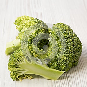 Raw broccoli on white wooden table, side view. Close-up