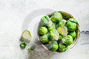Raw brussels sprouts in bowl, gray concrete background, top view. Healthy vegan food concept