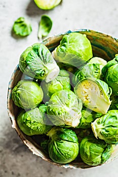 Raw brussels sprouts in bowl, gray concrete background, top view. Healthy vegan food concept