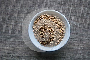 Raw Buckwheat in white ceramic bowl on wooden wood