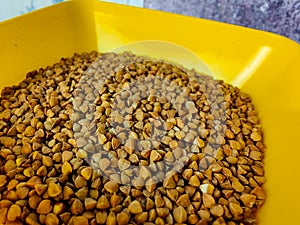 Raw buckwheat in a yellow plastic bowl.  Cereals.  Bulk products