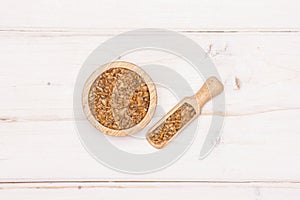 Raw bulgur grains on grey wood