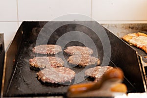 Raw burgers cooking on an iron