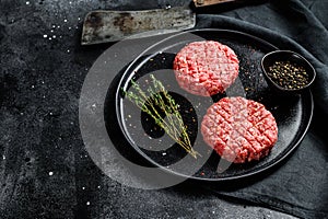 Raw burgers cutlets, organic ground beef meat. Black background. Top view. Copy space