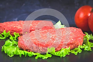 Raw burgers with lettuce on a gray background. Tomatoes, peppers